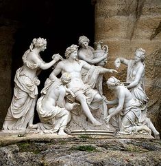 a group of statues sitting next to each other on top of a stone slab in front of a cave