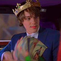 a young man in a blue suit with a gold crown on his head