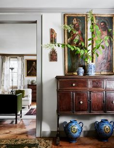 a living room filled with furniture and paintings on the wall