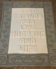 a crocheted afghan with words written in white and grey on the front side