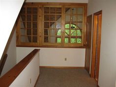 an empty room with wooden window frames and carpeted stairs leading up to the second floor