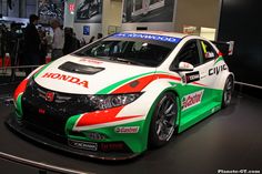 a honda civic racing car on display in a showroom with people looking at it