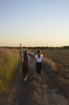 two people walking down a dirt road holding hands