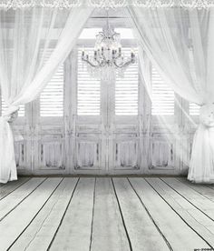 an empty room with white curtains and a chandelier