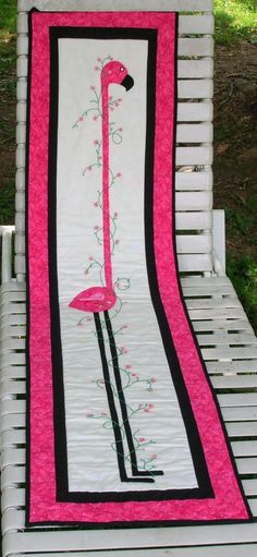 a pink flamingo quilted on top of a white bench