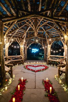 an outdoor wedding venue with candles and roses on the floor, surrounded by wooden arches