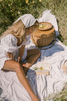 a woman sitting on top of a blanket next to a basket