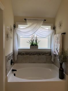 a bath tub sitting under a window next to a potted plant