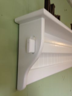 a white shelf mounted to the side of a green wall