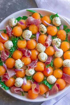 a white bowl filled with oranges and other food on top of a gray table