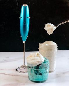 whipped cream being spooned into a jar with a blue glass in the foreground