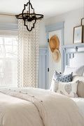 a bedroom with blue walls and white bedding has a chandelier hanging from the ceiling