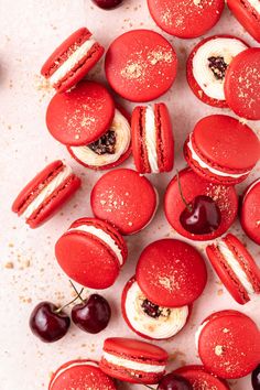 red macaroons with cream cheese and cherries are arranged on a white surface