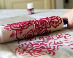 a person is using a sharp knife to paint the fabric on a bed sheet with red and white designs