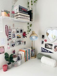 a white desk topped with books next to a lamp and other items on top of it