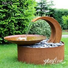 an outdoor fountain with rocks and water flowing from it's sides in the grass