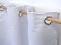 three white curtains with wooden handles hanging on the wall