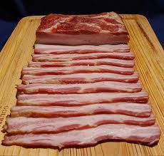 sliced bacon sitting on top of a wooden cutting board