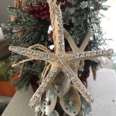 a starfish ornament hanging from a christmas tree with seashells on it