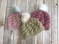 three knitted hats with white and pink pom - poms on wooden background