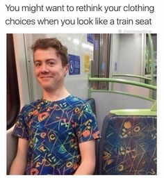 a man sitting on a train next to a green rail and smiling at the camera