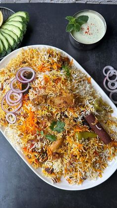 a platter filled with rice and vegetables next to other food items on a table