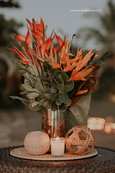 a vase filled with orange flowers sitting on top of a table next to a candle