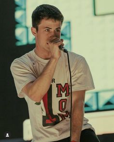 a man holding a microphone up to his mouth while standing in front of a stage