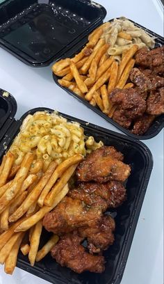 three black trays filled with different types of food on top of a white table