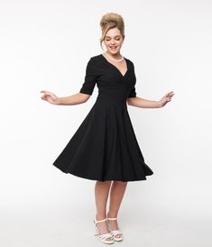 Let Delores get domestic with you, darling. A bewitching black frock rich in 1950s vintage dress appeal fresh from Unique Vintage, Delores is the flattering fit-and-flare dress you’ve been dreaming of! Boasting a gathered surplice V-neckline, trim and tailored mid-length sleeves with darling button detail, this swing dress also features a thick banded natural waistline that creates a minimized silhouette. An ample A-line full skirt billows to just below the knee in a soft pleated style, zipping Classic Black A-line Vintage Dress, Retro Black Fit And Flare Dress, 1950s Style Black Knee-length Dress, Retro Black Cocktail Dress, Black Tea-length Dress With Fitted Bodice, Classic Black Dress With Fitted Bodice, Black 1950s Style Cocktail Dress, 1950s Style Black Cocktail Dress, 1950s Style Fitted Black Vintage Dress