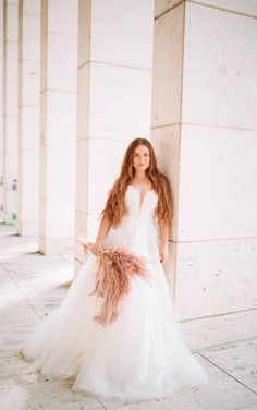 a woman in a wedding dress leaning against a wall