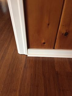 a wooden door with white trim on the bottom half and brown wood flooring below