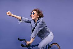 a woman is riding a bike with her arms in the air and she's smiling