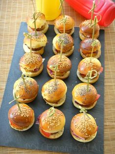 mini burgers with toothpicks are arranged on a mat