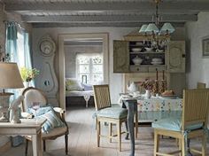 a living room filled with furniture and a dining table in front of a window on top of a hard wood floor