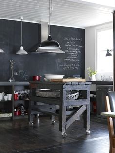 a kitchen with chalkboard walls and wooden flooring is pictured in this image, there are several chairs around the table