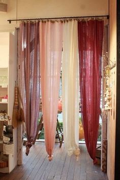 an open door with sheer curtains hanging from it's sides, in front of a wooden floor