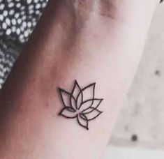 a woman's wrist with a small black flower tattoo on the left side of her arm