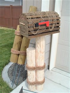 a mailbox made out of wood and rope on the side of a house in front of a door