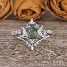 an engagement ring with a large green stone surrounded by white diamonds on top of a wooden table