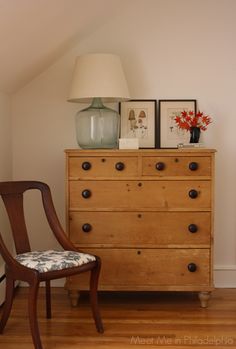 a wooden dresser sitting next to a lamp on top of a hard wood floor