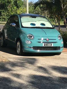 a blue car is parked on the side of the road in front of some trees