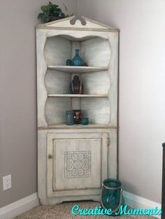 an old china cabinet painted white with blue vases on top