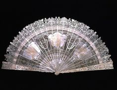 an ornately decorated white fan against a black background