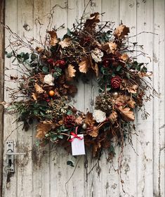 a wreath is hanging on the side of a door with leaves and berries around it