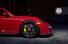 a red sports car parked in front of a building with the emblem on it's side