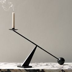 a black candle holder on a marble table with a white wall in the back ground