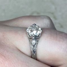 a close up of a person's hand holding a ring with a diamond in it