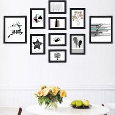 a white dining room table and chairs with pictures on the wall above it that have different shapes and sizes