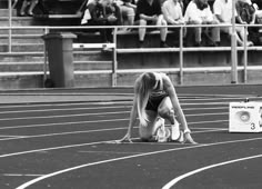 a woman kneeling down on top of a race track next to a box with numbers